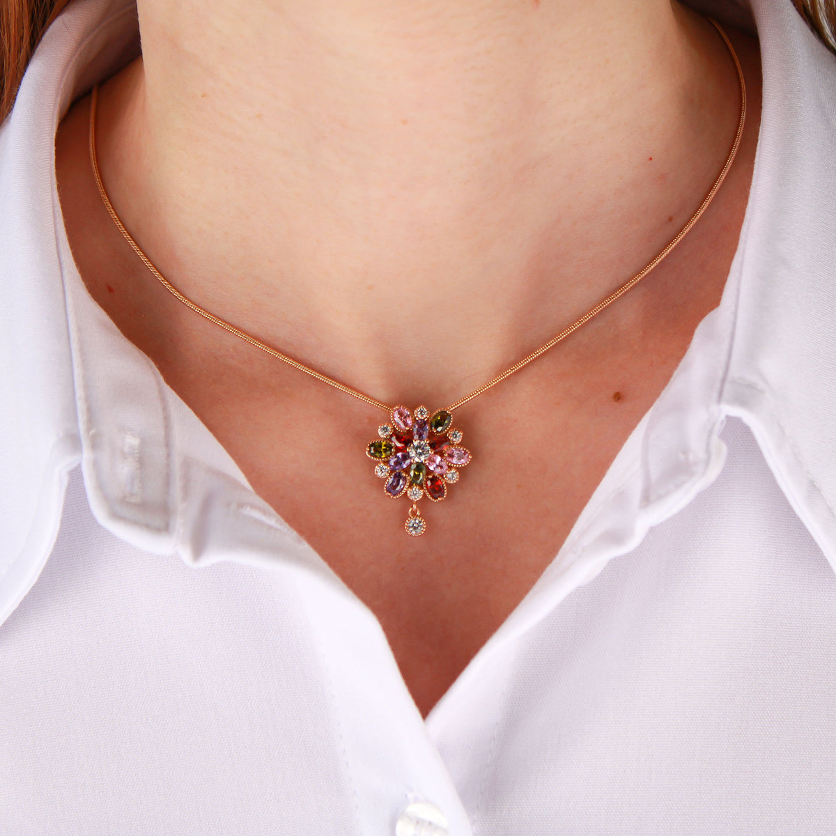 Flower pendant with colourful stones on a fine gold-plated chain on a model