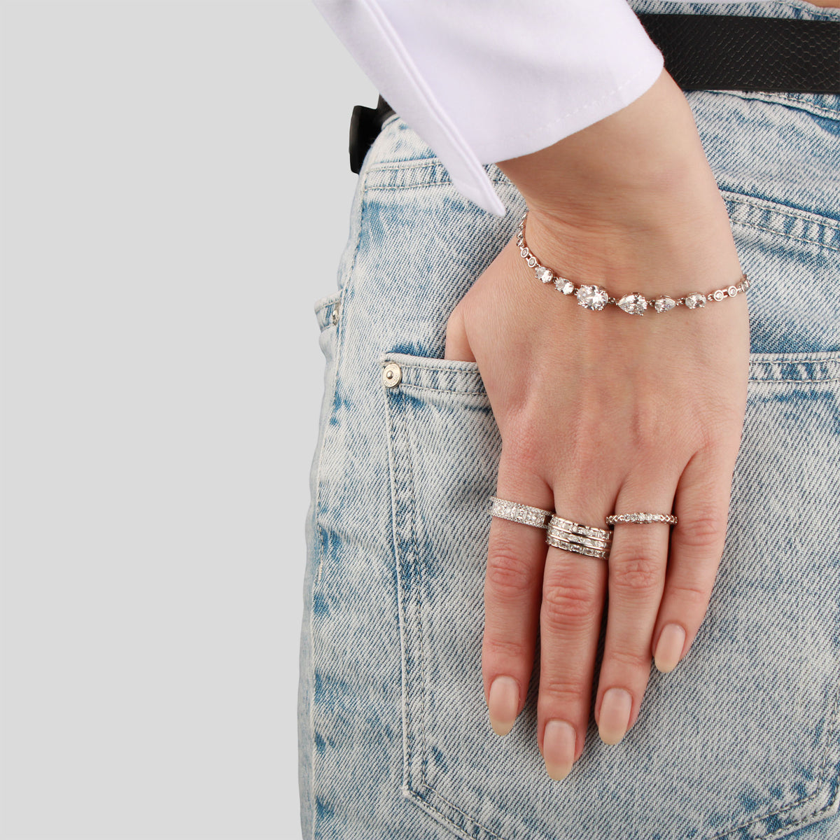 Silver-tone rings and a sparkling bracelet on a hand in a jeans pocket