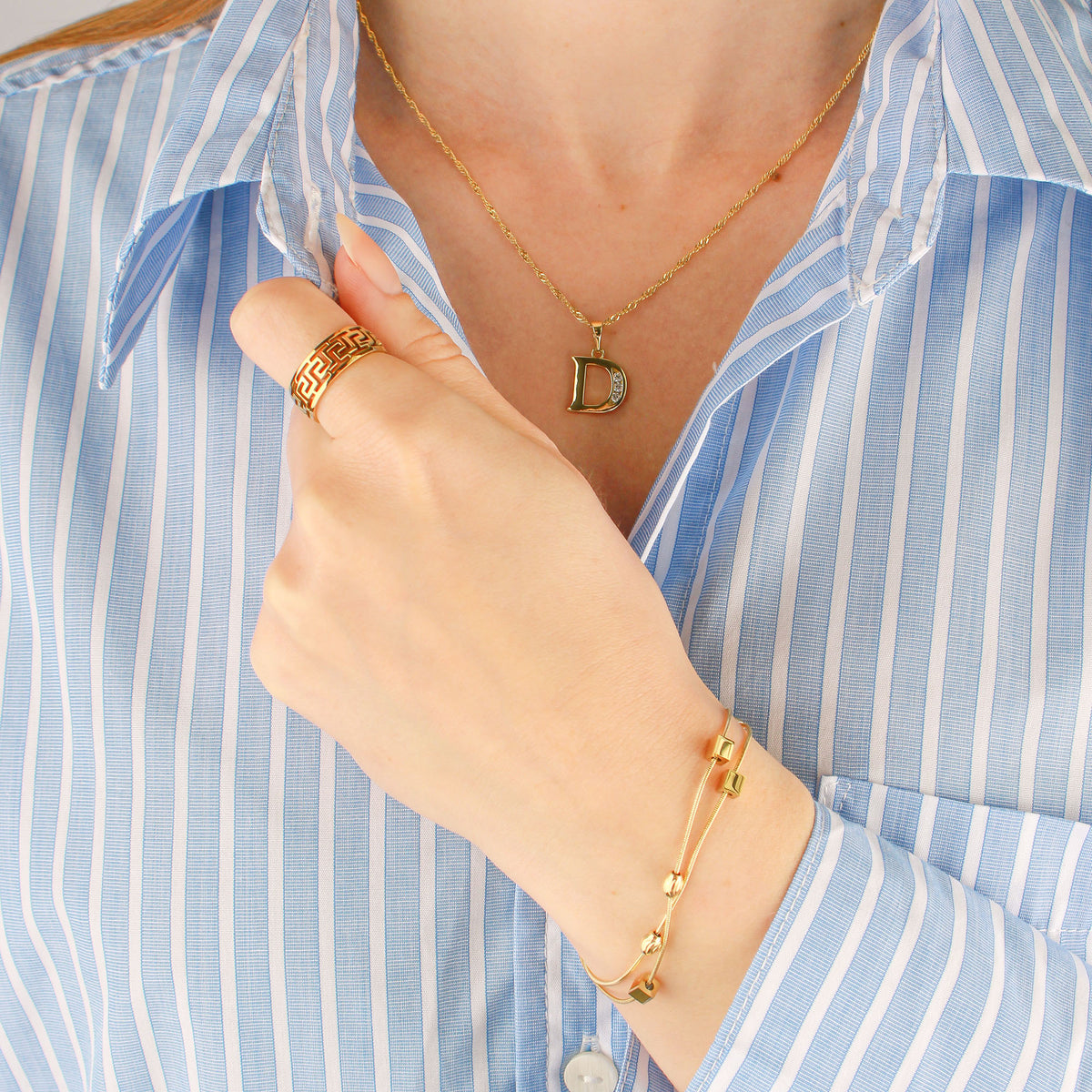 Model wearing a gold-plated Singapore chain with a letter D pendant, ring and bracelet