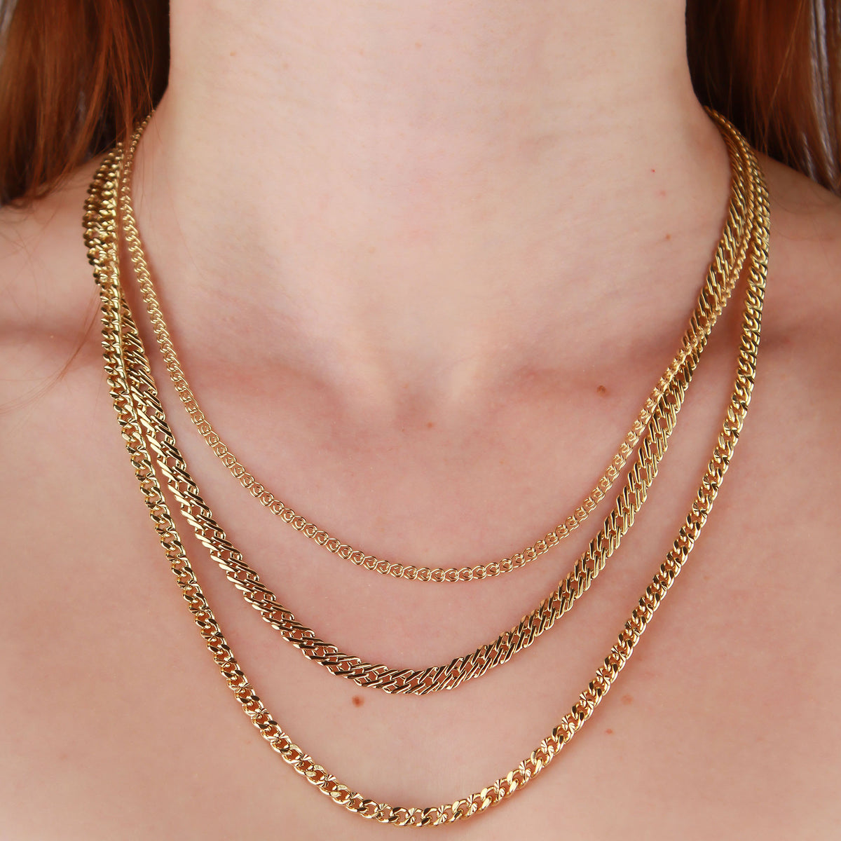 Gold-tone chains layered on a model's neck, showing the diamond-cut sparkle